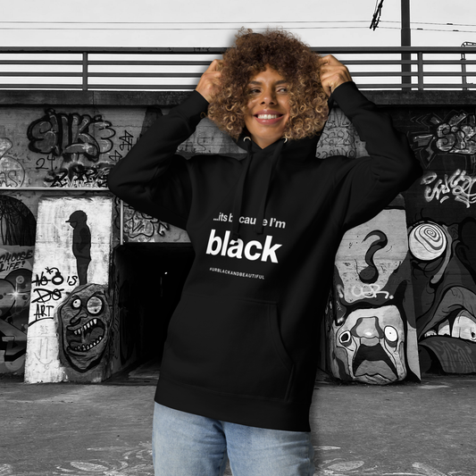 Person wearing a black hoodie with text, standing in front of graffiti art.