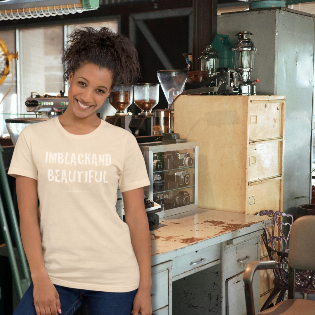 Woman wearing a 'IMBLACKAND BEAUTIFUL' t-shirt in a coffee shop setting
