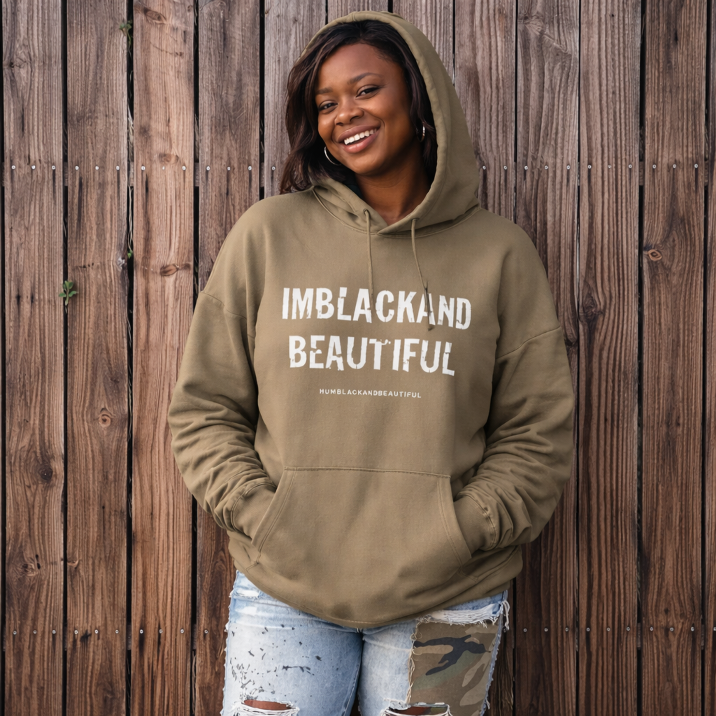 Person wearing a khaki hoodie with 'IMBLACKAND BEAUTIFUL' text against a wooden background
