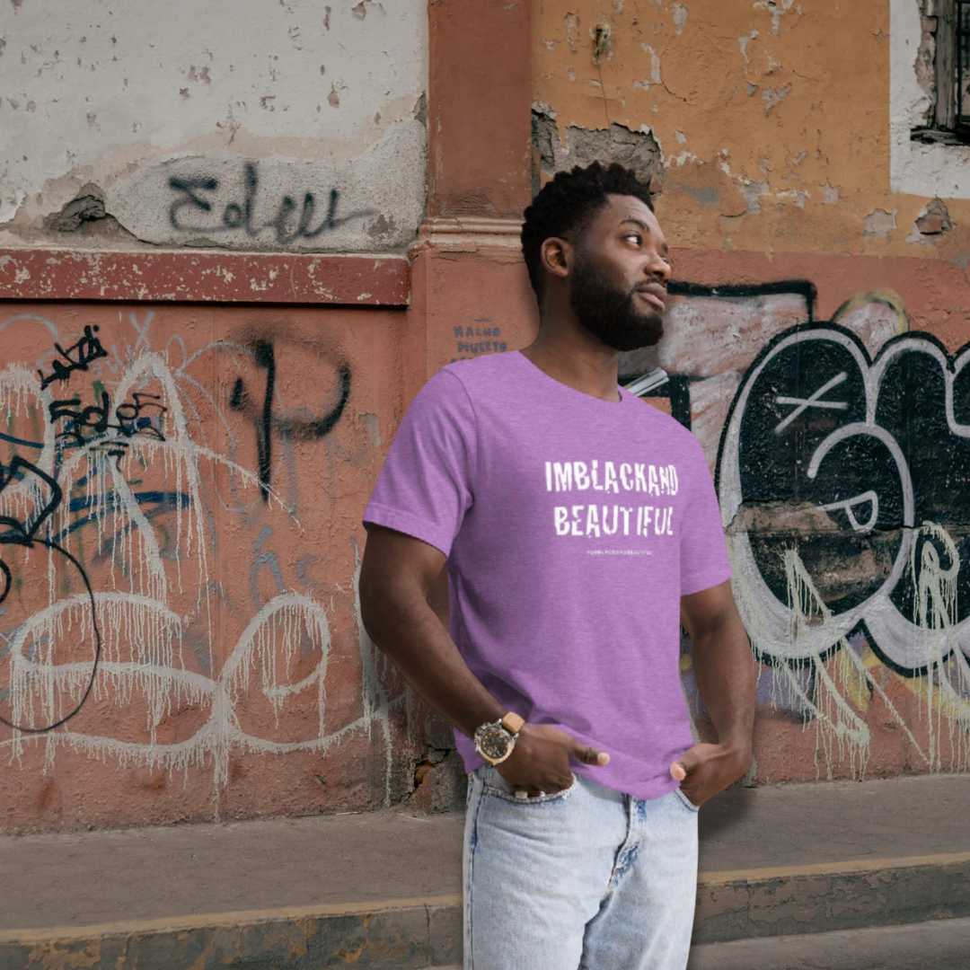 Man wearing a purple t-shirt with 'IMBLACKAND BEAUTIFUL' text, standing in front of a graffiti-covered wall.